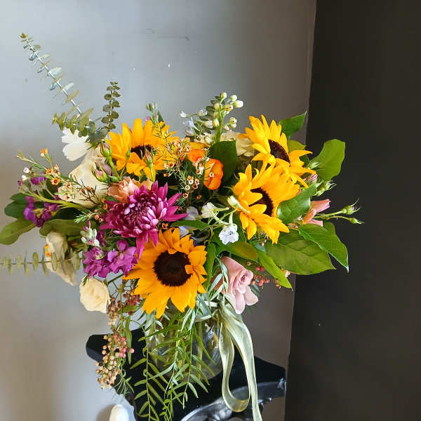 Bouquet of sunflowers, purple blooms, and mixed flowers in a black vase