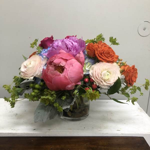 Mixed bouquet of pink, orange, and purple flowers in a glass vase