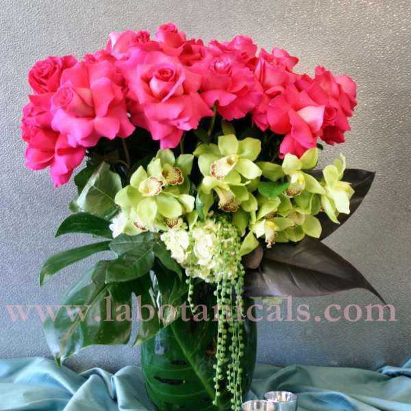 Pink roses and green orchids arranged in a glass vase