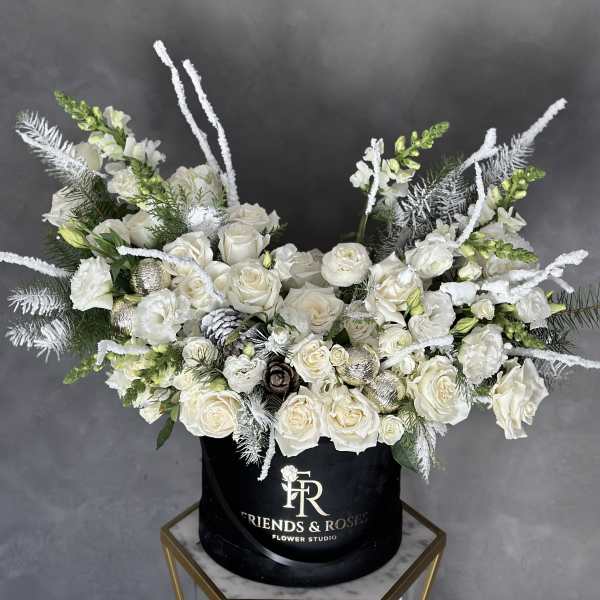 White roses and snapdragons arranged in a black hatbox.