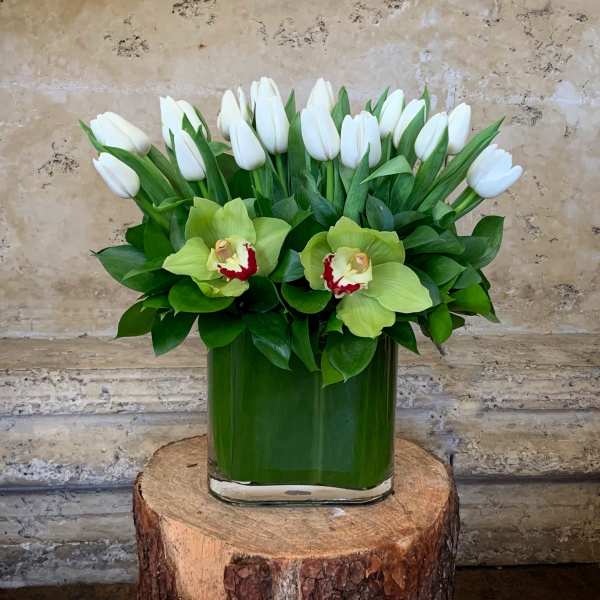 White tulips and green orchids in a glass vase