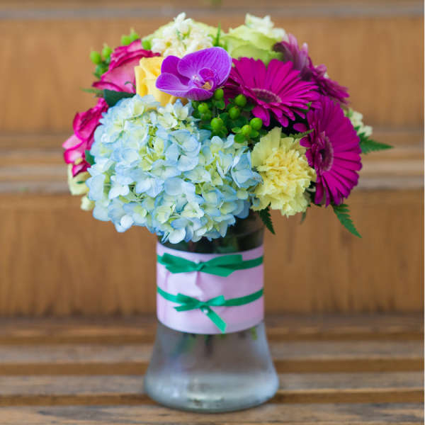 Colorful bouquet in a glass vase with hydrangeas, gerbera daisies, roses, and orchids