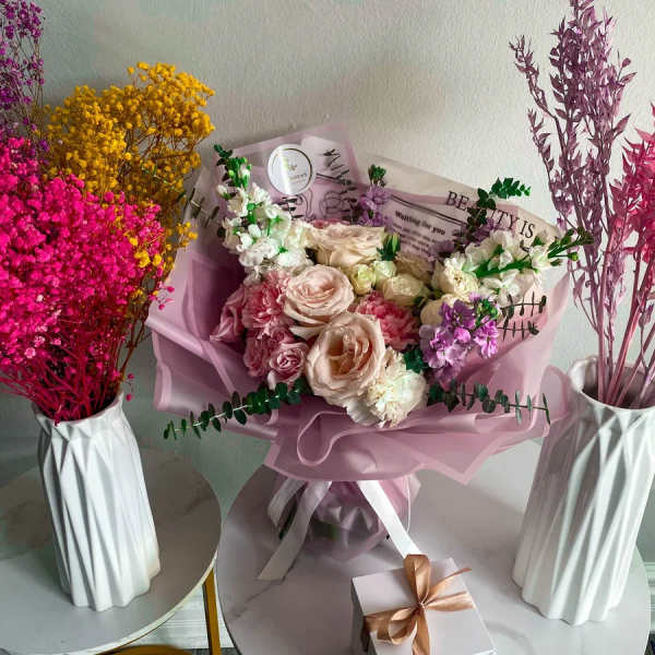 Pink and cream rose bouquet with purple accents in pastel wrap