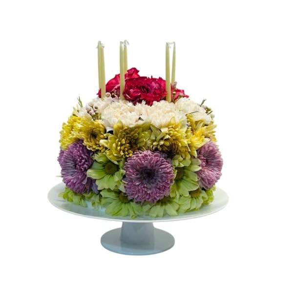 Round floral cake with candles on a pedestal stand