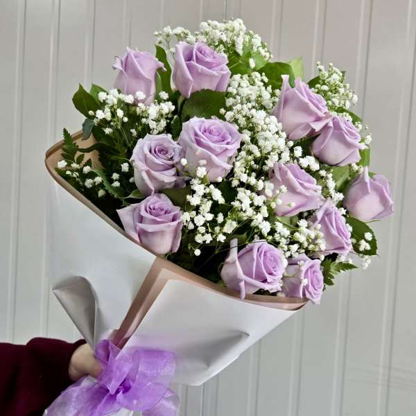 Bouquet of lavender roses and white baby's breath wrapped in paper