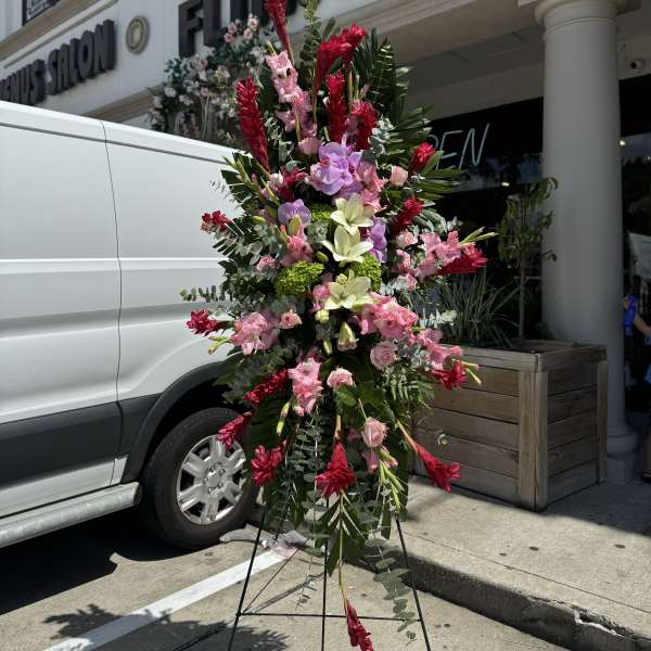 Tall standing floral spray with pink, red, and white blooms on an easel