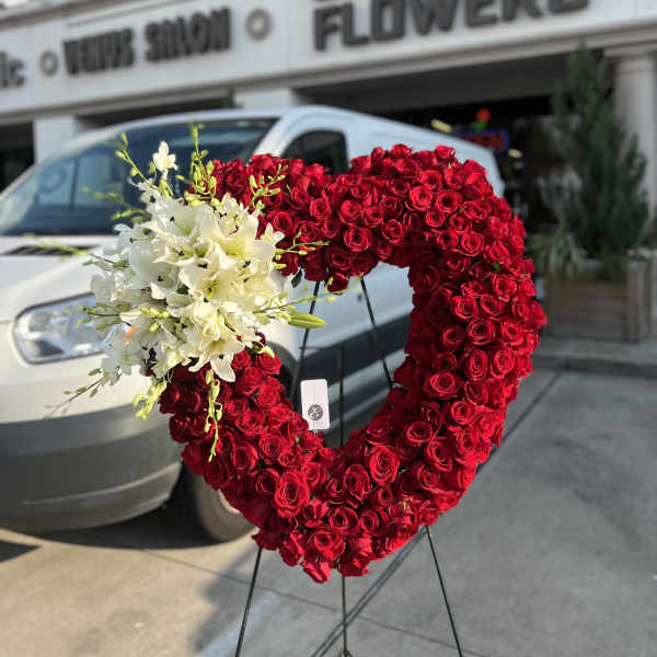 Heart-shaped red rose arrangement with white lilies on a stand