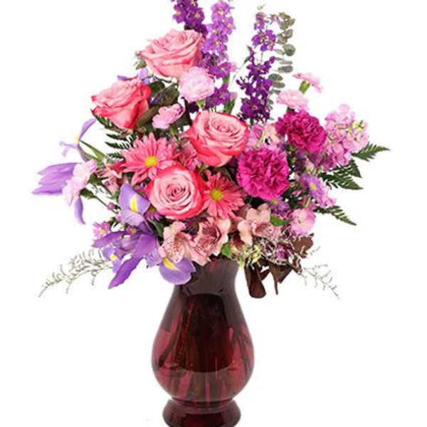 Pink and purple mixed flower arrangement in a red glass vase