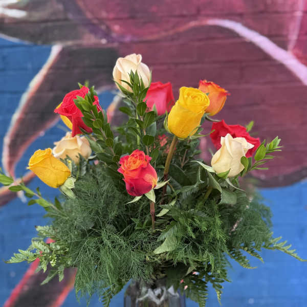 Mixed roses in a tall glass vase with greenery