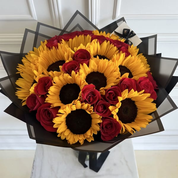 Bouquet of yellow sunflowers and red roses wrapped in layered black paper