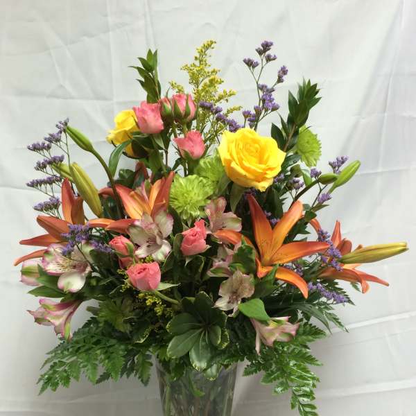 Mixed bouquet of roses, lilies, and alstroemeria in a glass vase