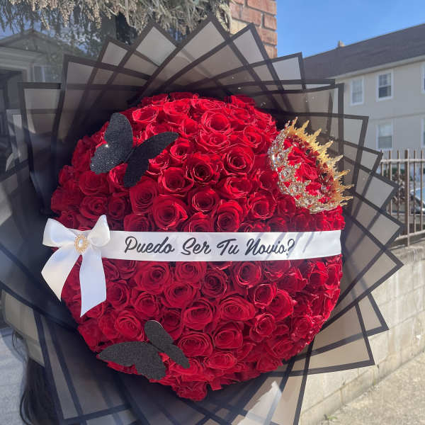 Large bouquet of red roses with a white ribbon and black wrap