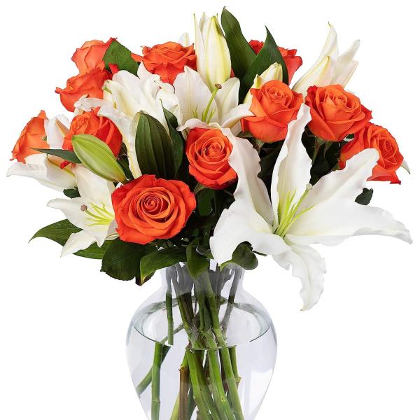 Arrangement of orange roses and white lilies in a clear glass vase