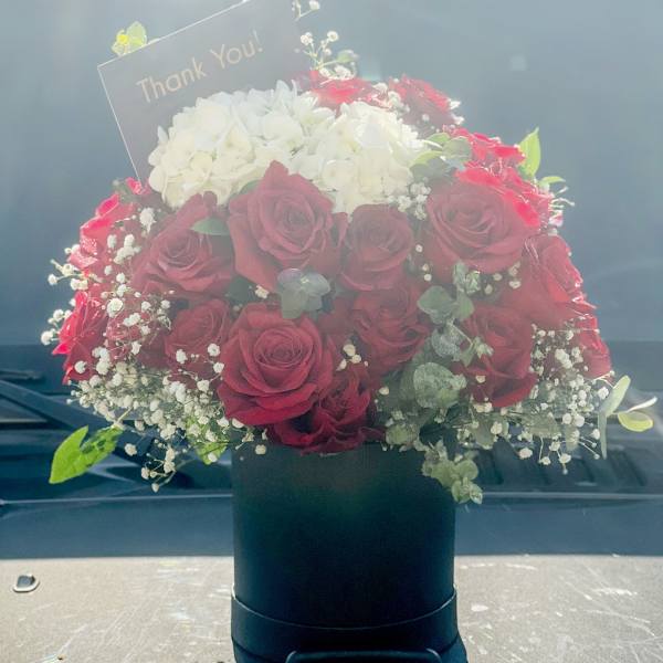 Bouquet of red and white roses with a thank-you card in a black box