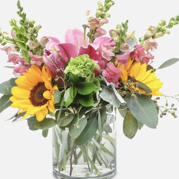 Bouquet of sunflowers and pink flowers in a clear glass vase