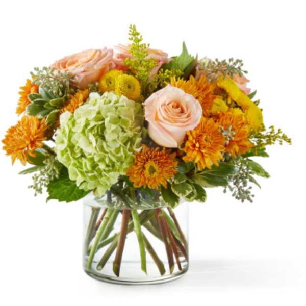 Peach roses and orange mums in a clear glass vase