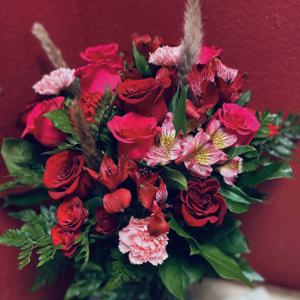Bouquet of red roses and pink flowers with greenery