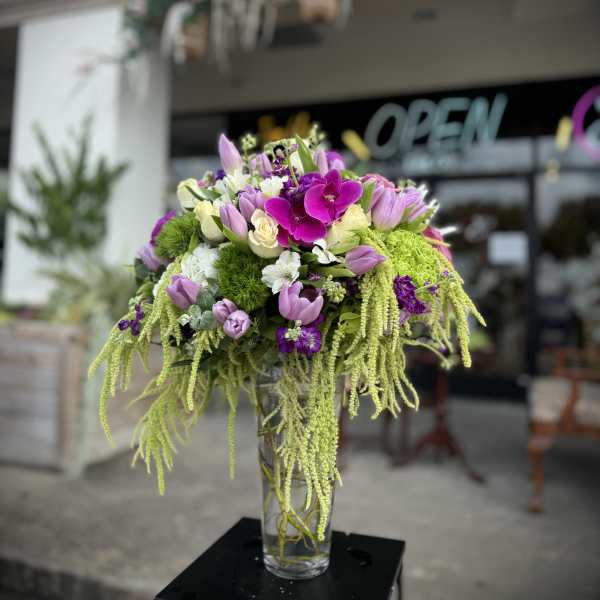 Purple and white floral arrangement in a clear glass vase