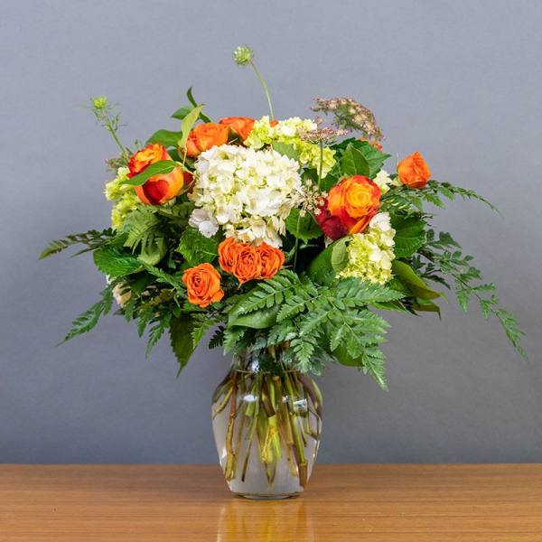 Orange and white rose bouquet in a clear glass vase