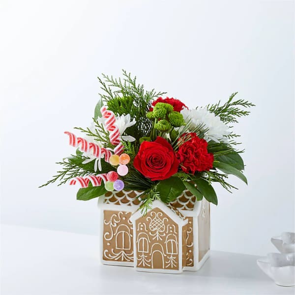 Christmas floral arrangement in a gingerbread house container with candy canes