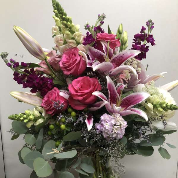 Pink roses and lilies arranged in a clear glass vase
