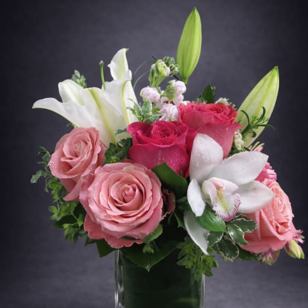 Pink roses and white lilies arranged in a clear glass vase