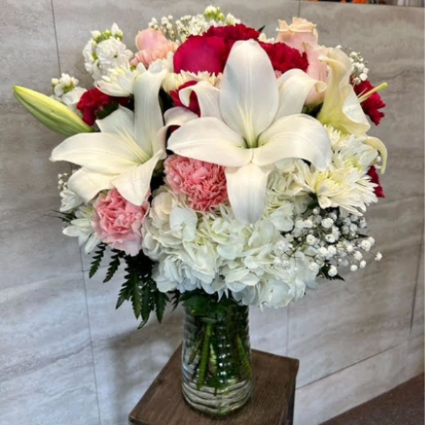 Bouquet of white lilies, red and pink flowers in a glass vase