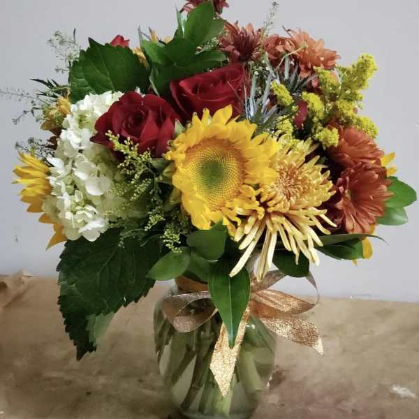 Mixed bouquet with roses, sunflowers, and chrysanthemums in a glass vase