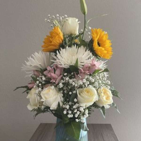 Mixed bouquet in a blue glass vase with white, pink, and yellow flowers