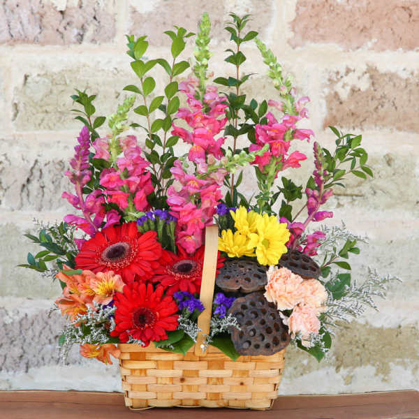 Colorful flower basket with gerbera daisies, snapdragons, and lotus pods