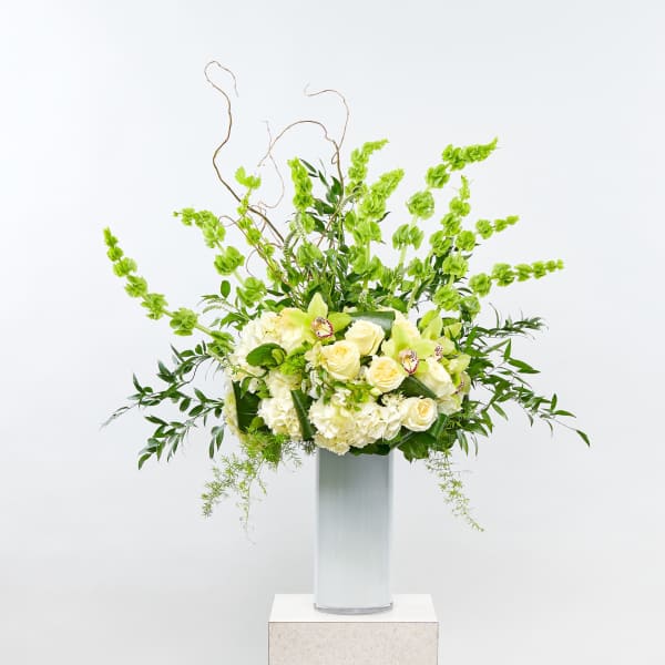 Tall white and green floral arrangement in a clear vase