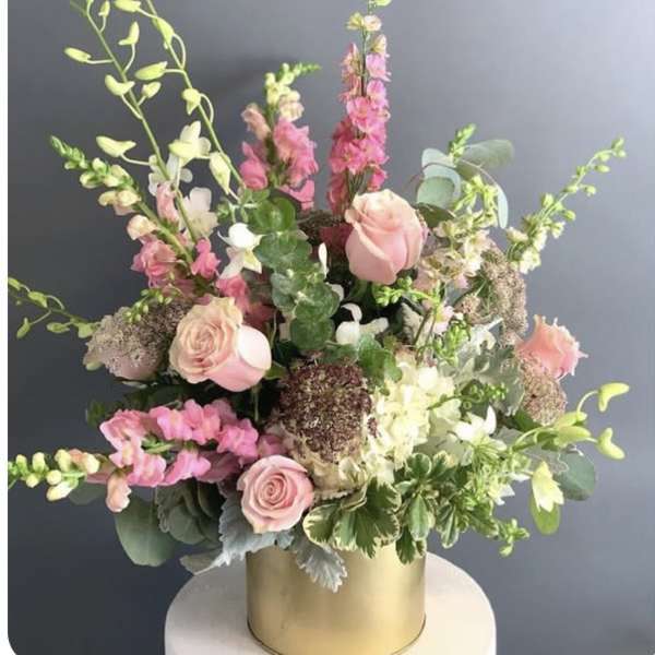 Pink and white floral arrangement in a gold cylinder vase