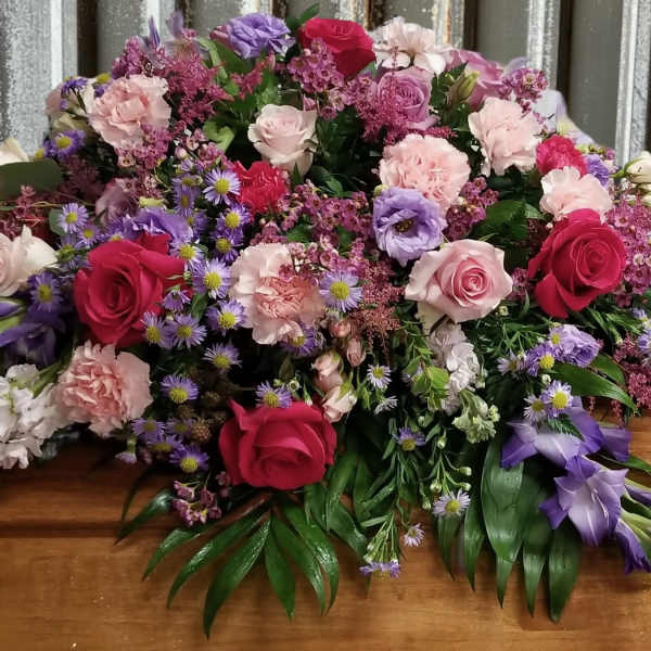Large casket spray with pink, purple, and red flowers