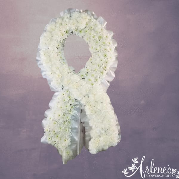 White floral funeral wreath with a ribbon border on a purple background