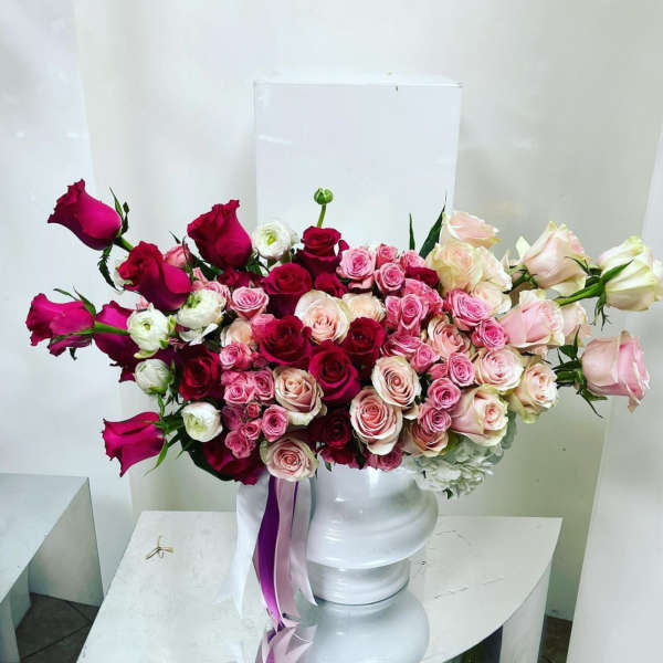 Bouquet of pink and red roses in a white pedestal vase