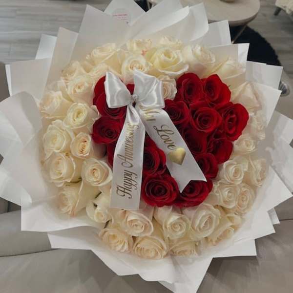 Bouquet of red and white roses wrapped in white paper with a satin bow
