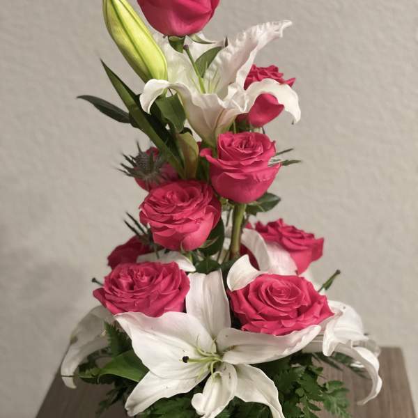Pink roses and white lilies arranged in a black vase