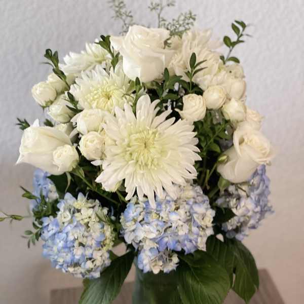 White and pale blue flowers arranged in a glass vase