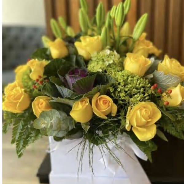 Yellow roses and lilies arranged in a white box
