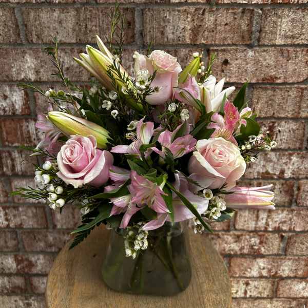 Pink roses and lilies arranged in a glass vase