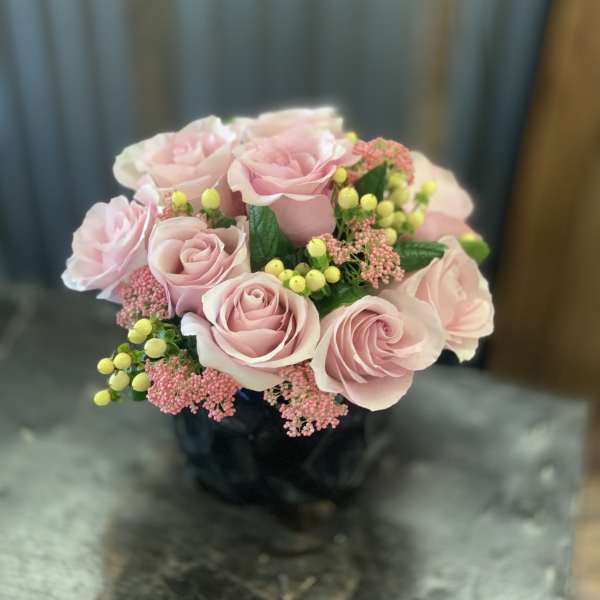 Pink rose bouquet with yellow berry accents in a dark vase