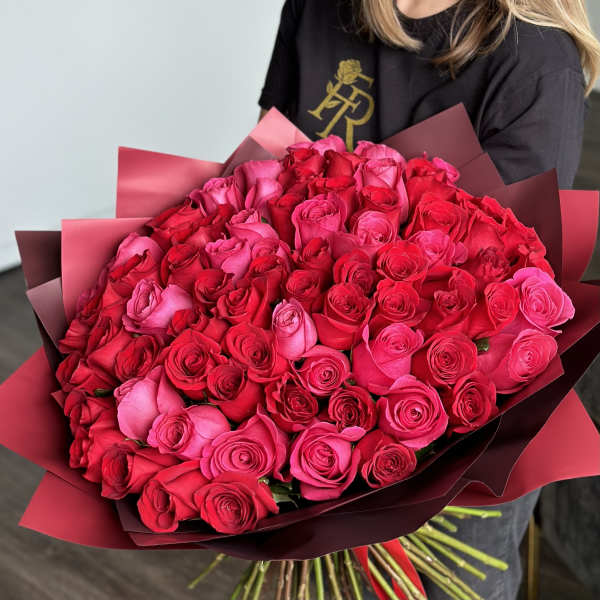 Large bouquet of pink and red roses wrapped in burgundy paper