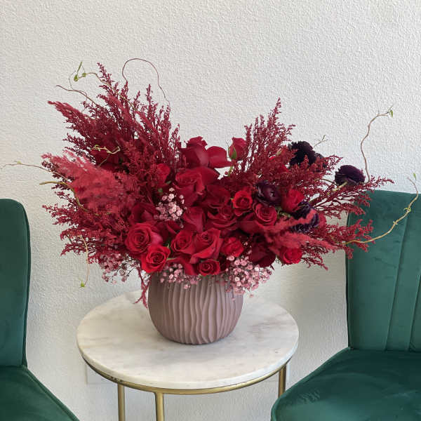 Red rose arrangement in a ribbed pink vase on a small round table