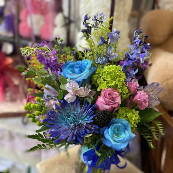 Colorful bouquet with blue and pink roses in a glass vase