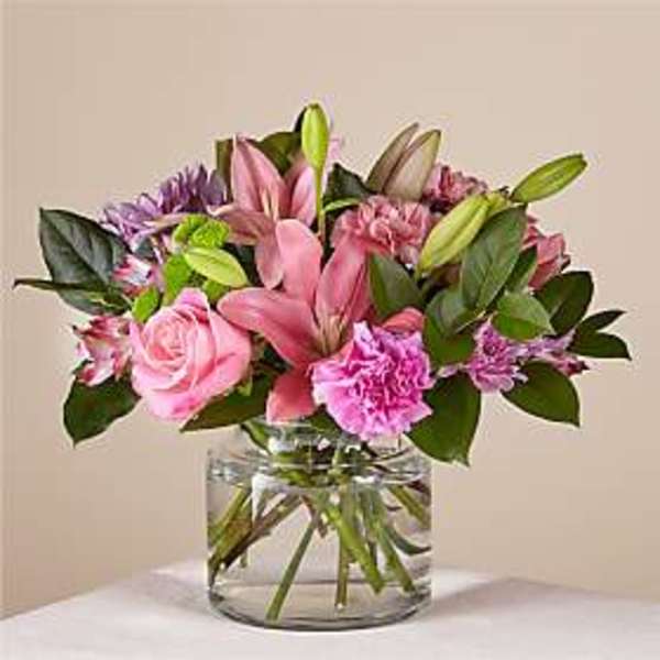 Pink lilies and roses in a clear glass vase