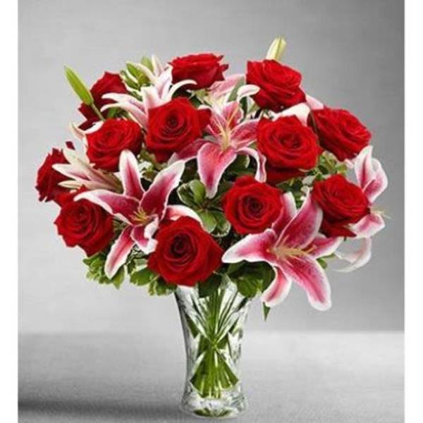 Arrangement of red roses and pink lilies in a clear glass vase
