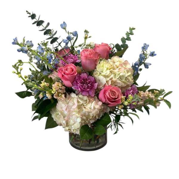 Pink roses and hydrangeas in a glass vase with blue accent flowers