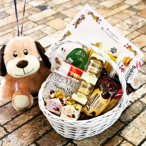 Gift basket with cookies, chocolates, and a plush dog