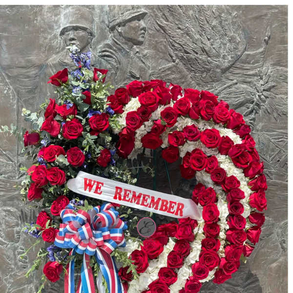 Large red and white rose wreath with a "WE REMEMBER" ribbon