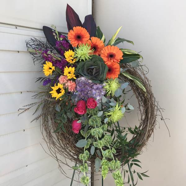 Colorful floral wreath on a stand with orange, purple, yellow, and pink blooms